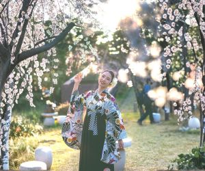 満開の桜の下で微笑む女性が着物姿で立つ華やかなポートレート