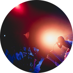 強いライトを浴びながら観客に向けて歌うアーティストのライブシーン