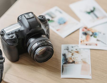 カメラと机に並べられたプリント写真の静物カット