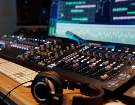 音響ミキサーやモニターが並ぶ制作デスクのクローズアップ