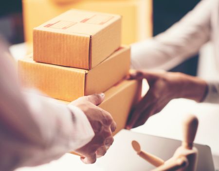 段ボール箱を手渡しする人の手元を写した受け渡しシーン