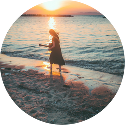 夕陽が差す海辺で楽器を持つアーティストのシルエット写真