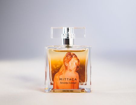 ガラスボトルに彫像が映し出された高級感あるデザインの香水ボトルを撮影した商品写真。