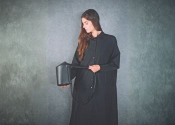 シンプルな背景でバッグを持つ女性モデルを撮影したイメージ写真