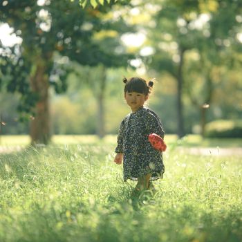 柔らかな光の中、草原を歩く幼い女の子の自然な姿