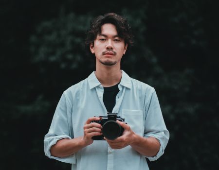 カメラを構えるフォトグラファーが静かに前を見つめるポートレート写真。